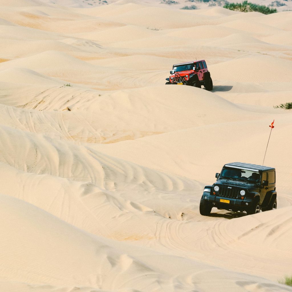 Four-wheel-drive vehicles crossing sand dunes on a desert safari