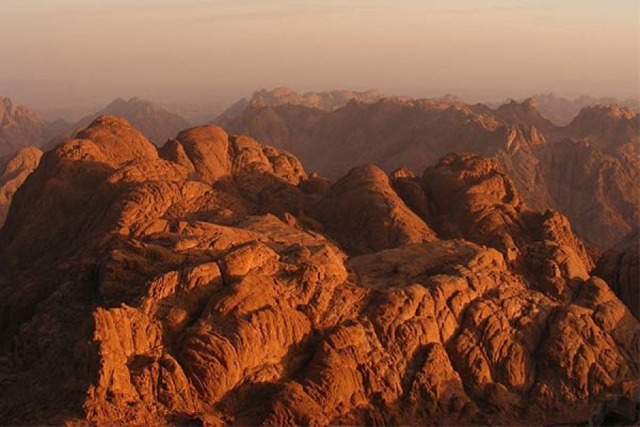 reddish-brown granite peaks of Mount Sinai (Gabal Musa), showing its barren and dramatic desert landscape under a vast sky, evoking its spiritual significance