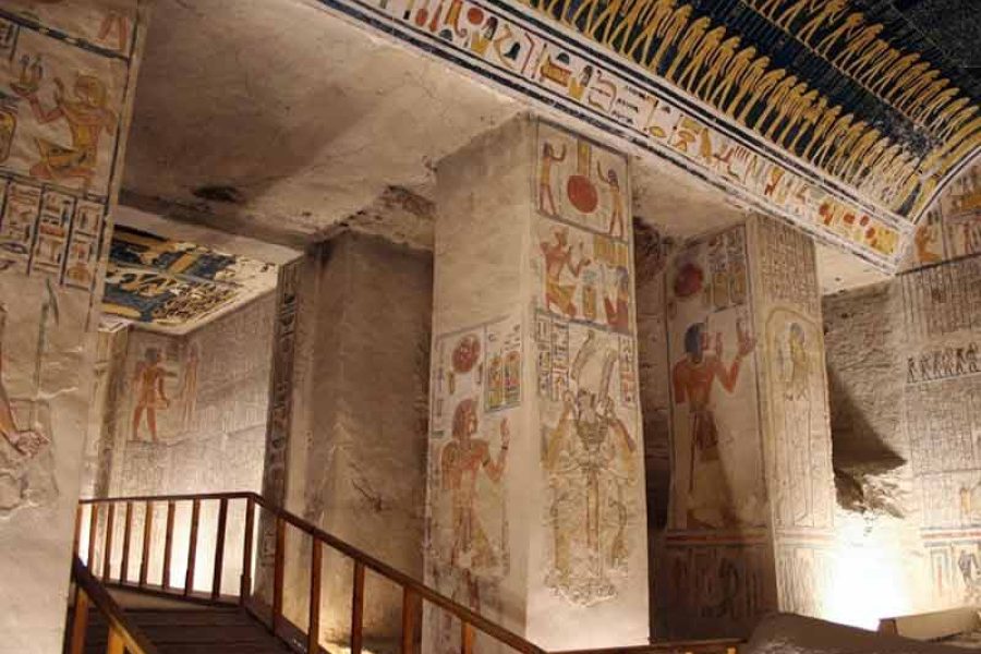 A sweeping view of the archaeological site of the Valley of the Kings, showing its numerous tomb entrances, visitor paths, and the surrounding desert mountains, reflecting its historical importance