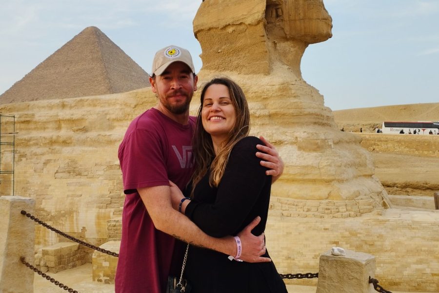 A couple posing affectionately in front of the majestic Great Sphinx of Giza, with the ancient monument and a clear sky forming a classic romantic backdrop