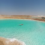 A client effortlessly floating on the highly buoyant, crystal-clear waters of a salt lake in Siwa Oasis
